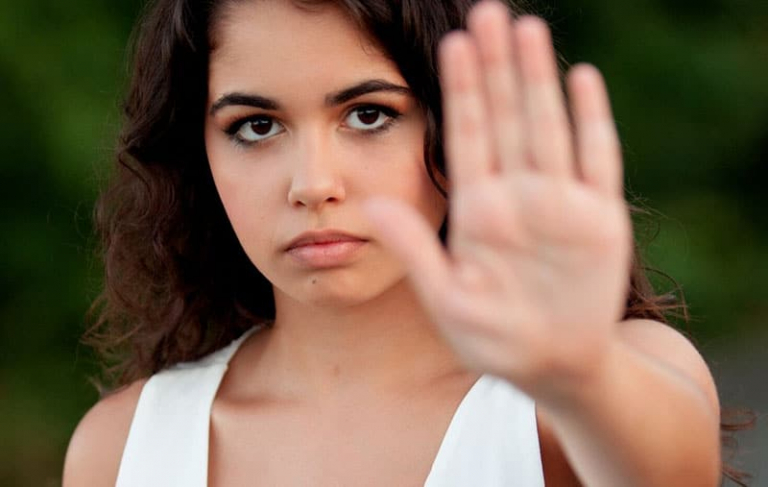 woman i white top making a stop hand gesture
