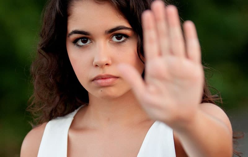 woman i white top making a stop hand gesture