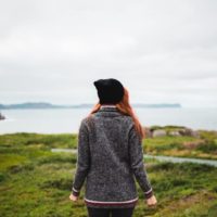 mulher de camisola cinzenta de pé num campo de relva verde