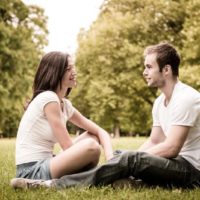 woman in white t-shirt and man sitting on grass