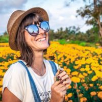 mulher com chapéu a segurar uma flor amarela