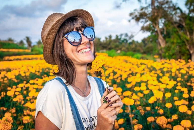 woman with hat holding yellow flower