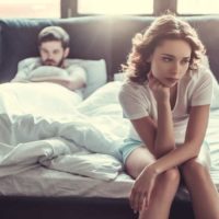 sad woman sitting on bed near man