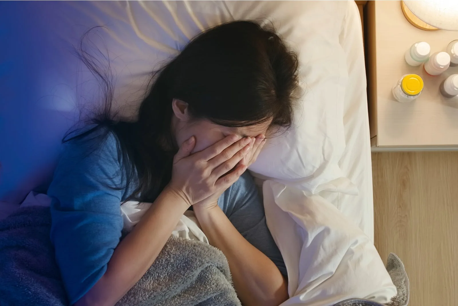 a depressed asian woman lies in bed and cries
