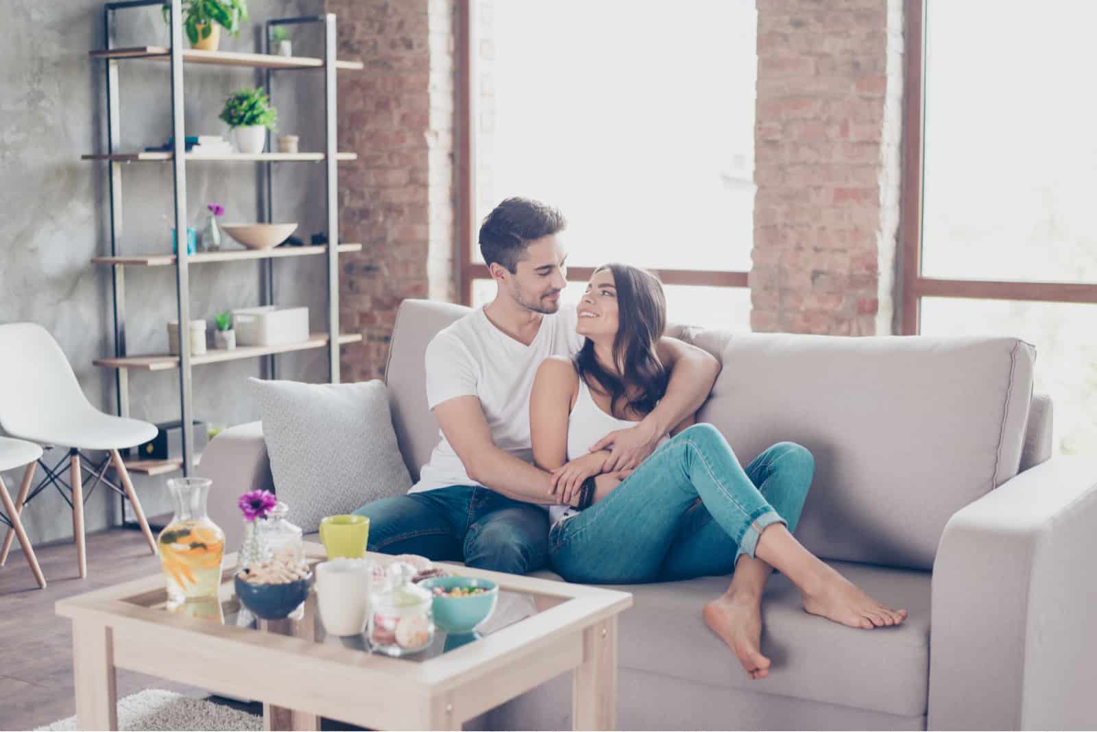 a happy couple cuddles on the sofa