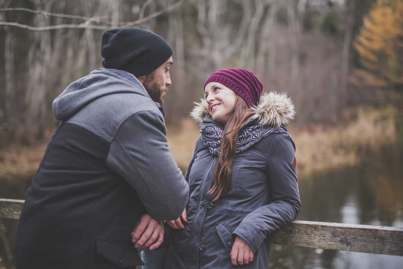 una pareja feliz conversa en un puente de madera