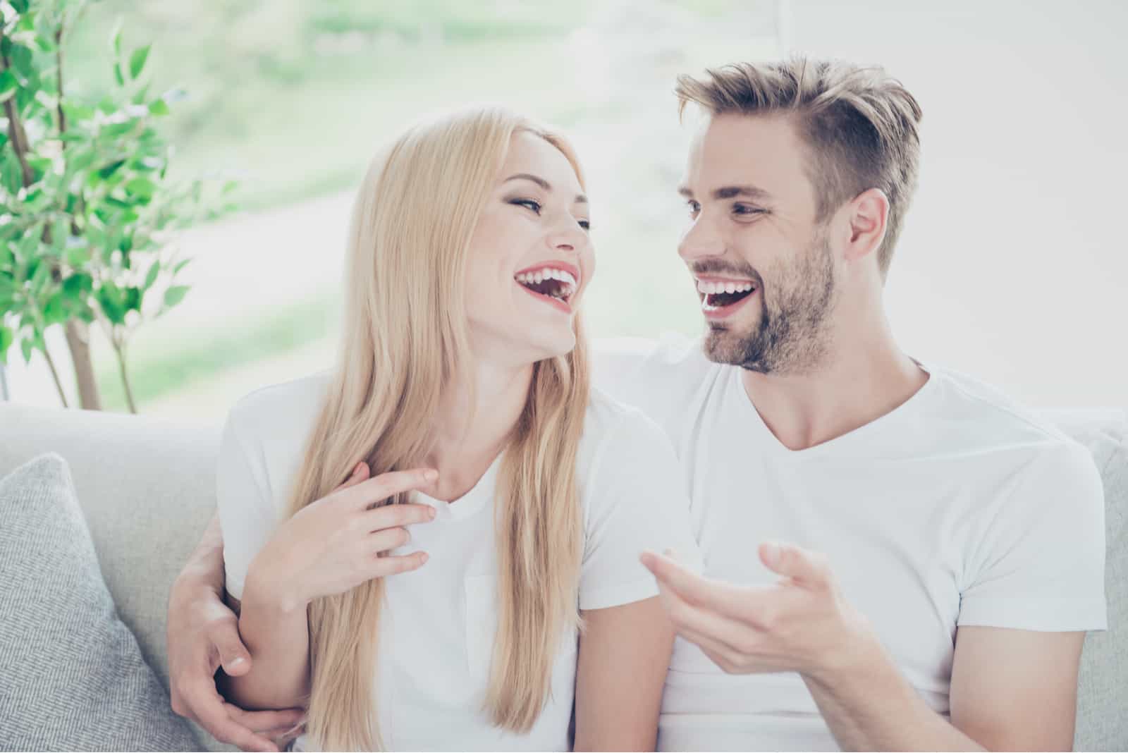 a smiling couple sits in the house and talks