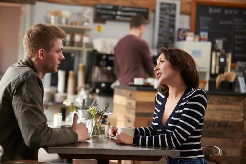 Coppia di adulti che parla all'interno di un caffè, vista laterale