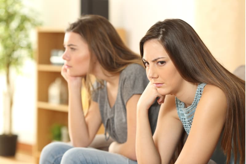 angry friends roommates sitting together in a sofa inside living room