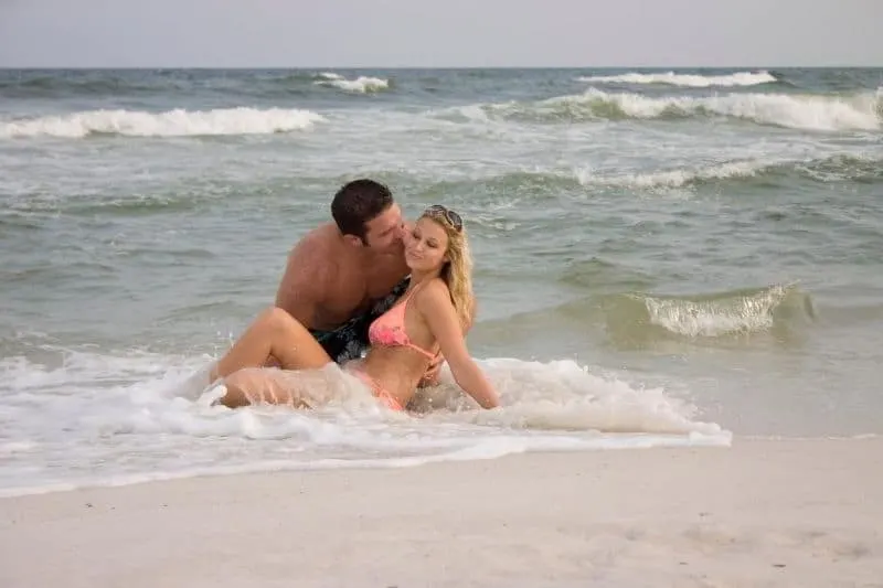 beach lovers enjoying the sea man kissing the woman wearing swimsuit