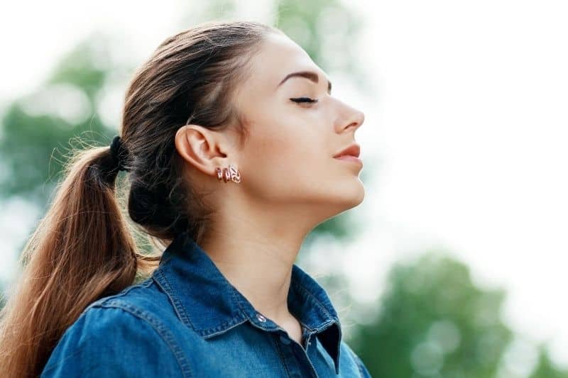 hermosa mujer respirando aire fresco al aire libre con top azul