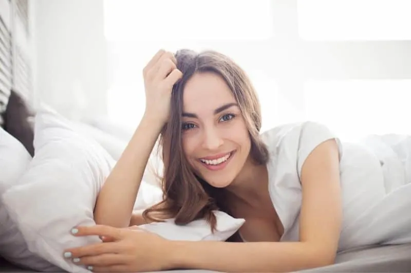 beautiful woman lying on white bedroom smiling