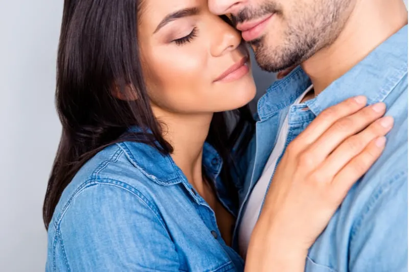 closed cropped portrait of woman smelling and hugging her man