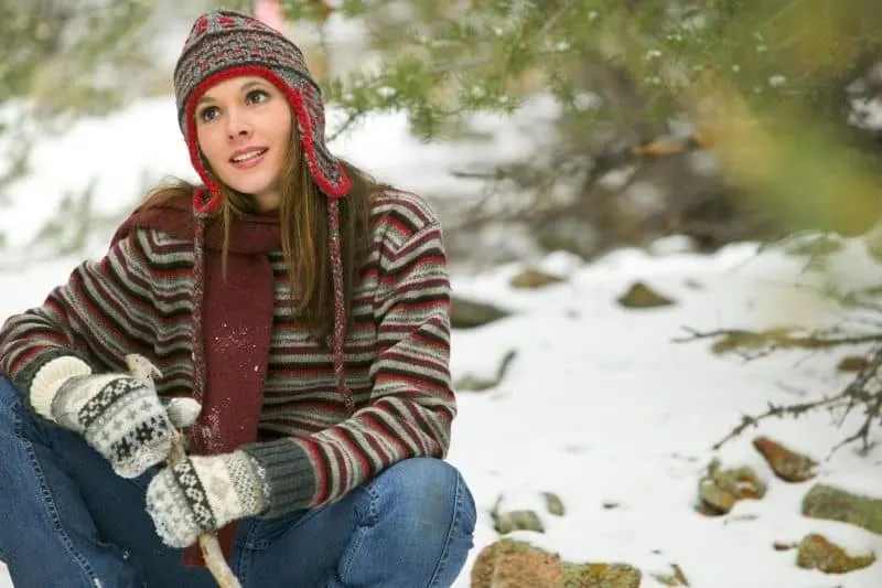 content woman sitting outdoors in a snowy location wearing winter clothes