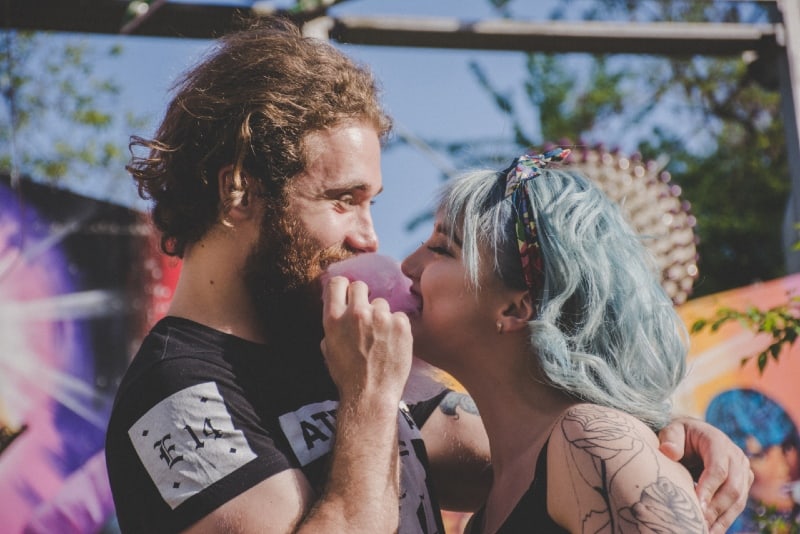uomo e donna sorridenti che mordono lo zucchero filato rosa