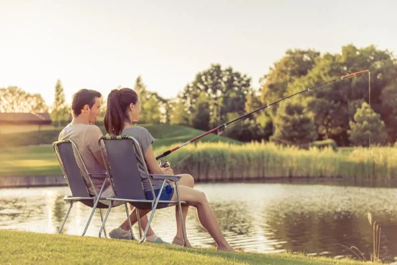 man and woman catching fish while sitting on chairs