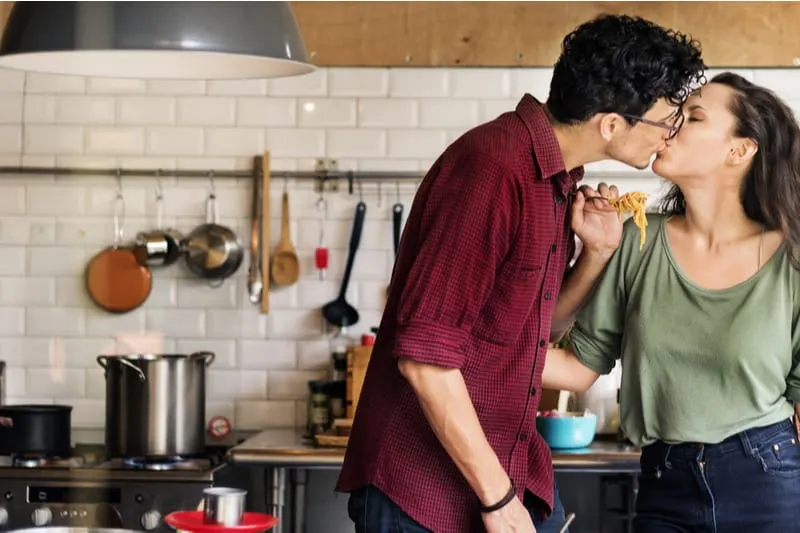 couple cooking hobby while kissing inside kitchen