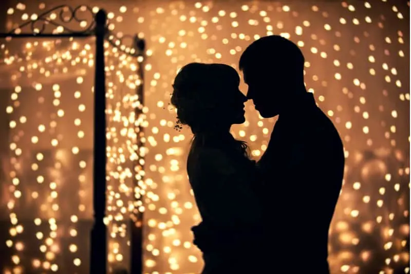 couple dancing silhouette hugging with face to face and lights all around