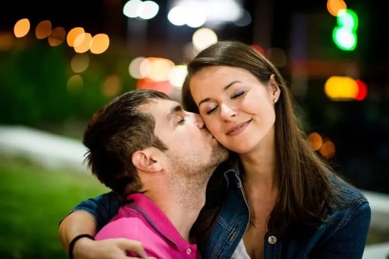 couple dating at night outdoors man kissing the woman's cheek