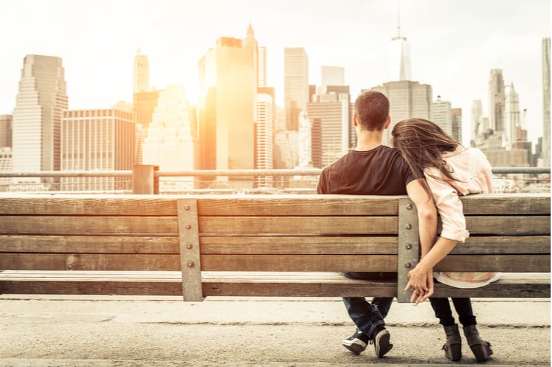 couple dating in new york bench facing the tall skyscrapers