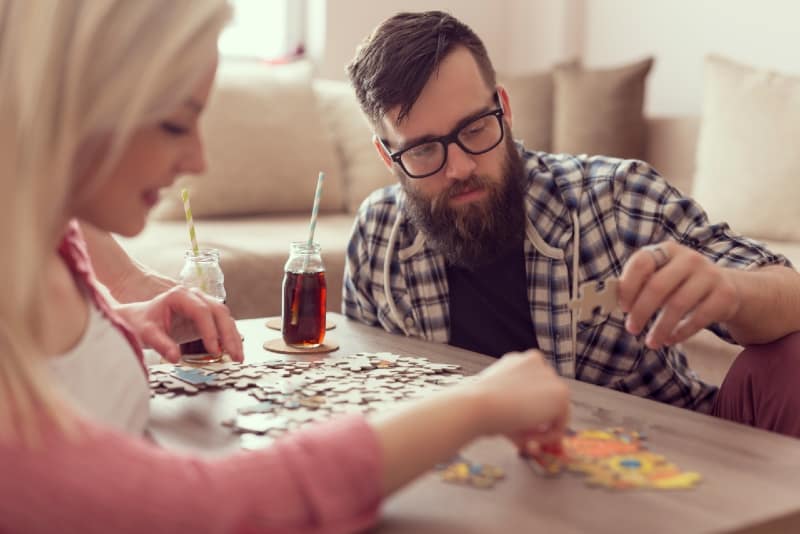 uomo e donna che fanno un puzzle seduti sul pavimento