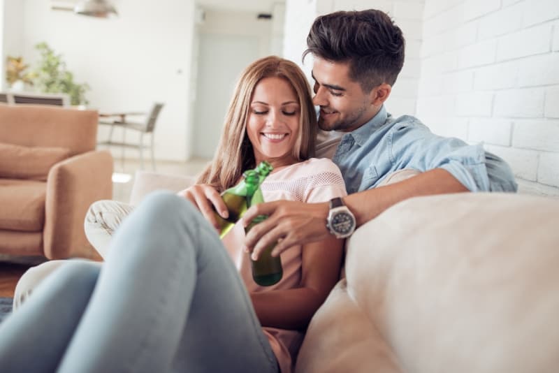 hombre y mujer bebiendo cerveza sentados en el sofá