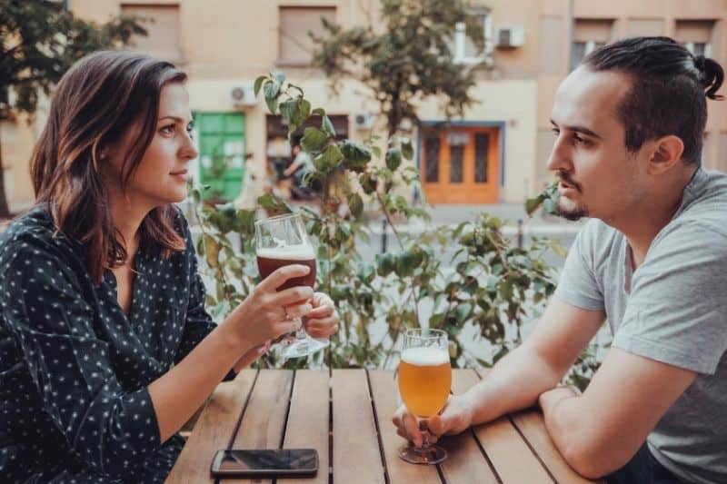 coppia che beve birra all'aperto parlando seriamente