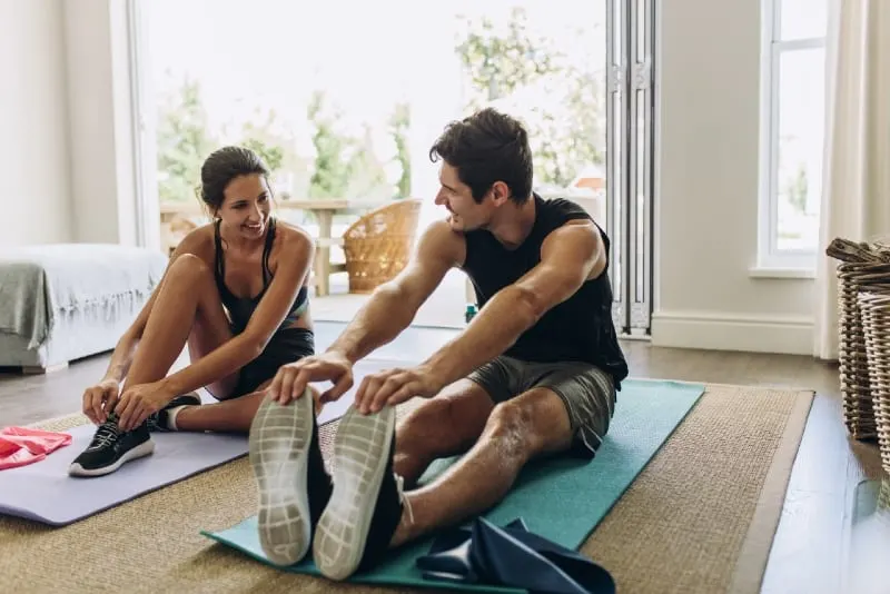 man and woman in sports wear exercising at home