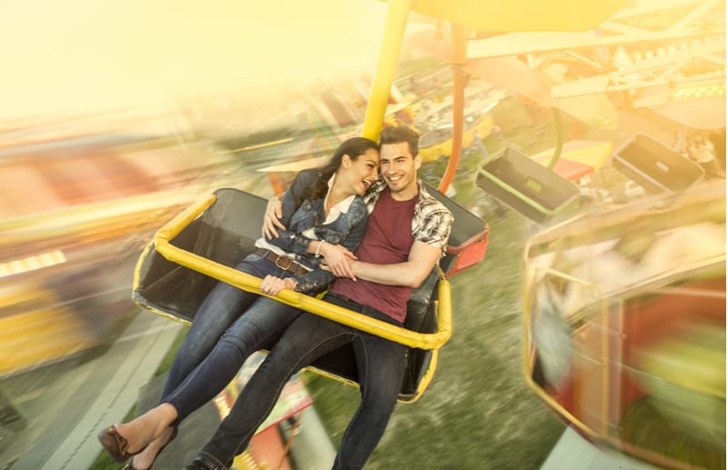 pareja divirtiéndose en el parque de atracciones montada en un tiovivo