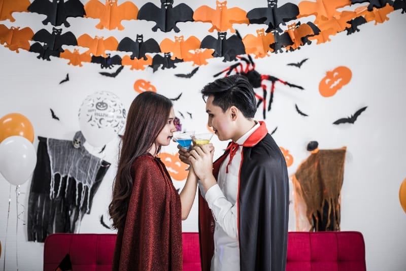 man and woman in halloween costumes holding drinks