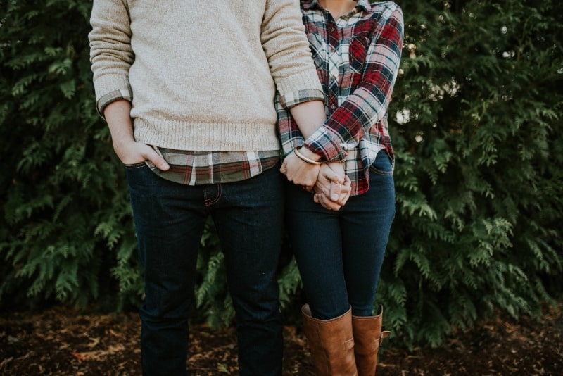 woman in plaid shirt and man holding hands