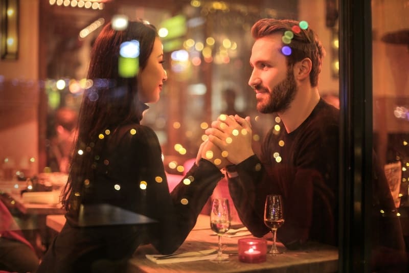 man and woman holding hands while sitting at table