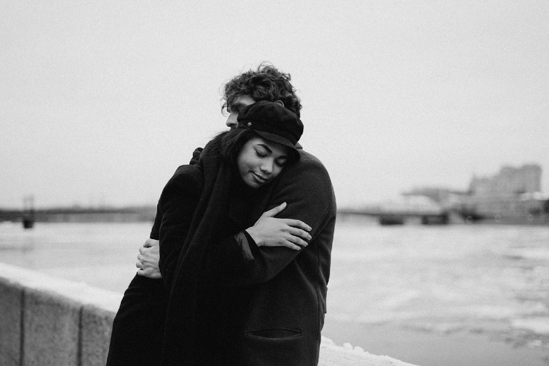 man and woman hugging while standing near water
