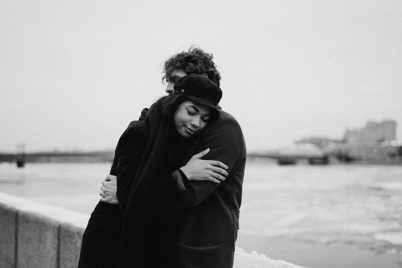 man and woman hugging while standing near water
