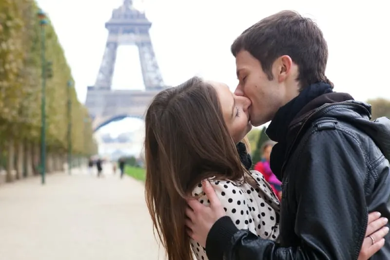 man and woman kissing near eiffel tower