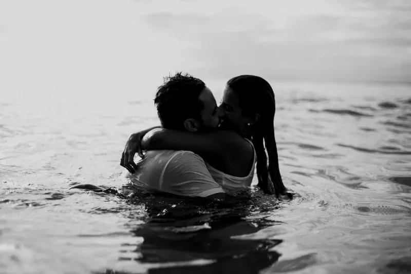 man and woman kissing while standing in water
