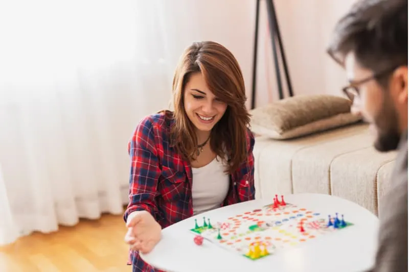 couple playing boardgame inside home during the day