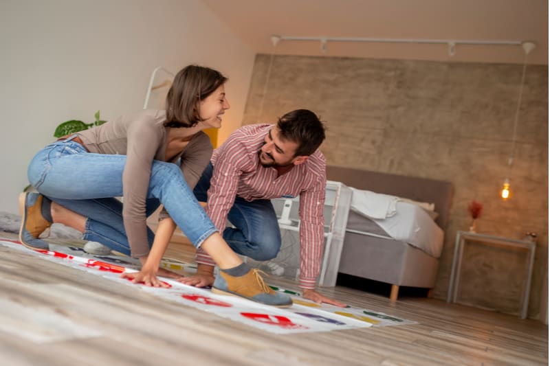 couple playing game twister having fun inside the living room