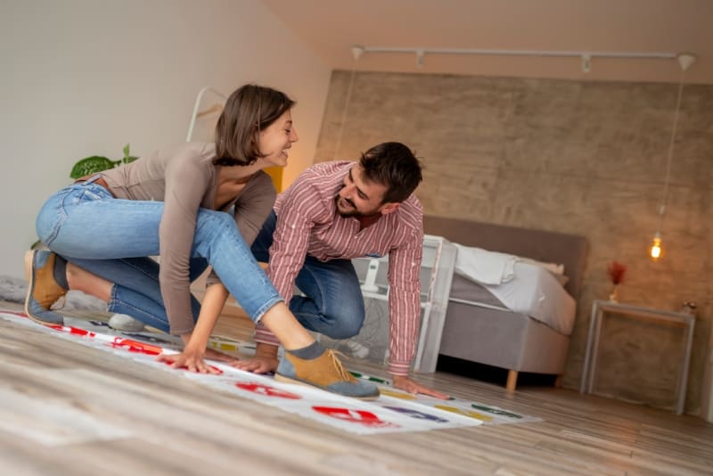 homem e mulher a jogar twister no interior