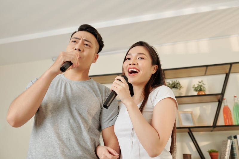 uomo e donna che cantano una canzone tenendo in mano un microfono