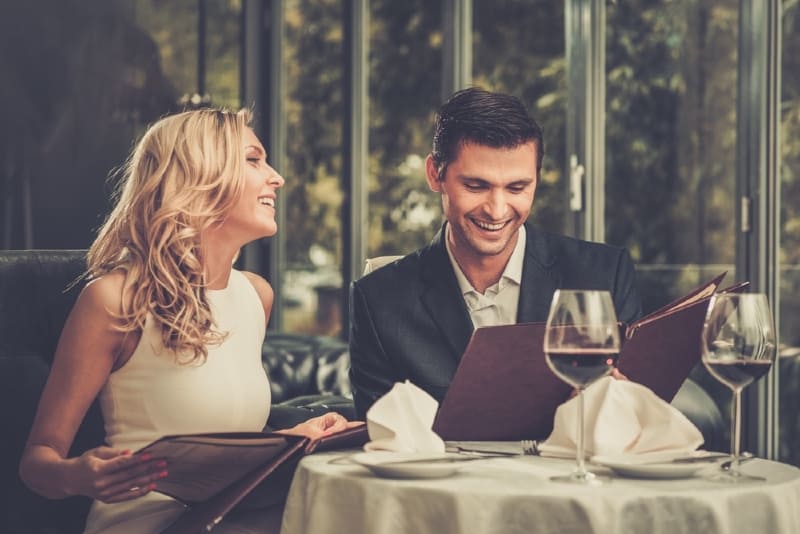 hombre y mujer sentados a la mesa y bebiendo vino