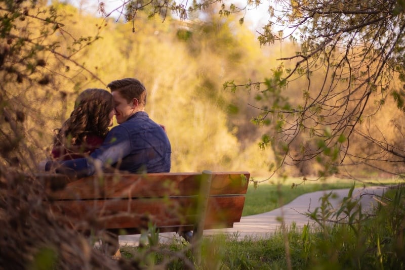 man hugging woman while sitting on bench