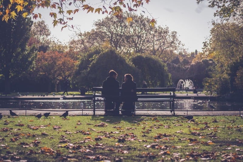 man and woman sitting on bench near river