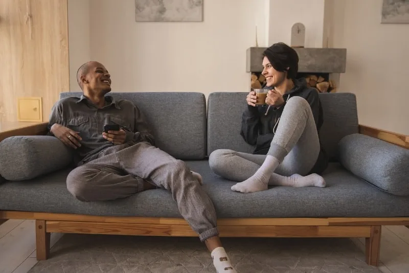 man with phone and woman sitting on couch and talking