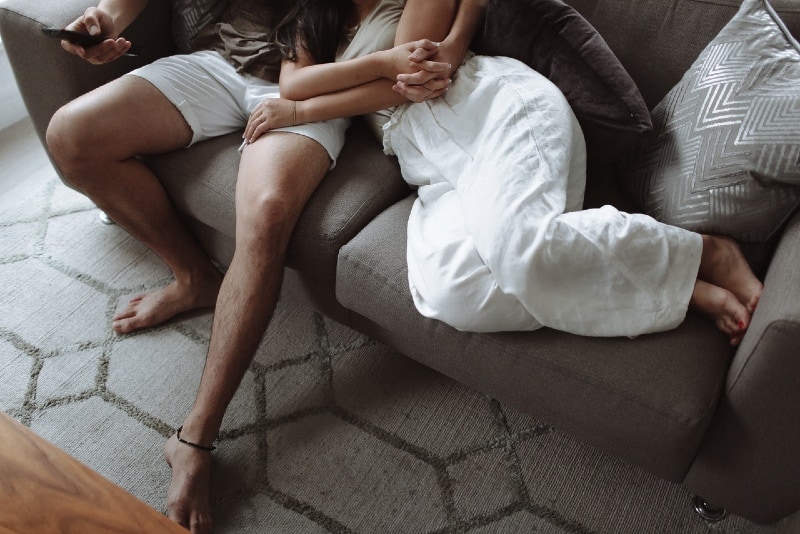 man and woman holding hands while sitting on sofa