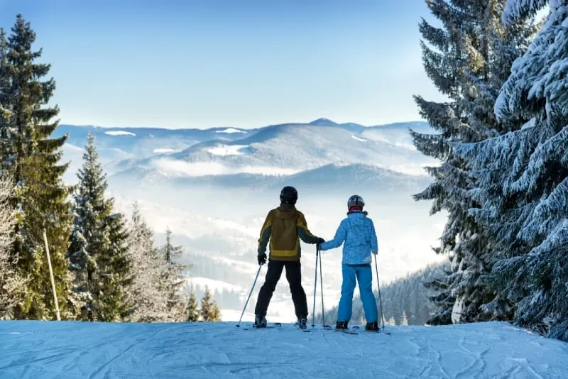 man and woman holding hands while skiing