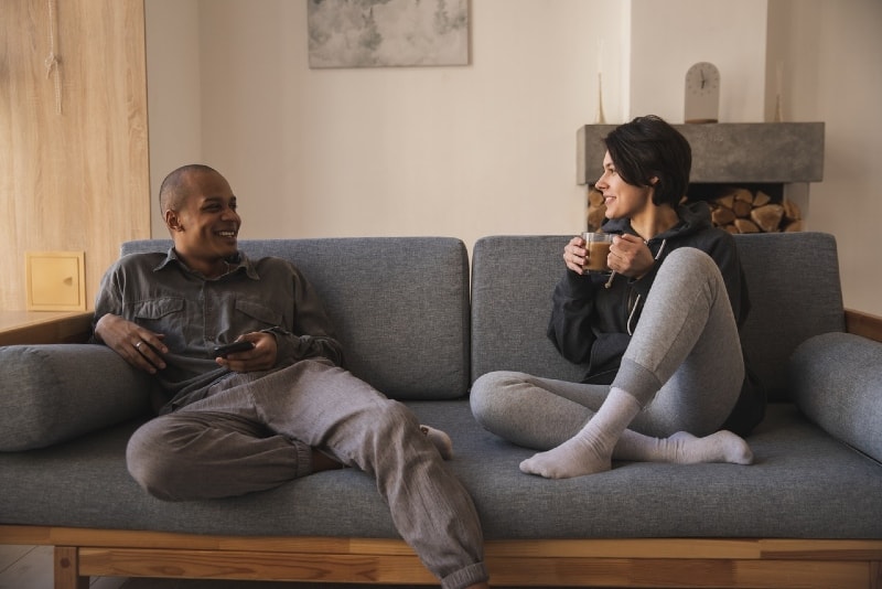 smiling man and woman talking while sitting on sofa