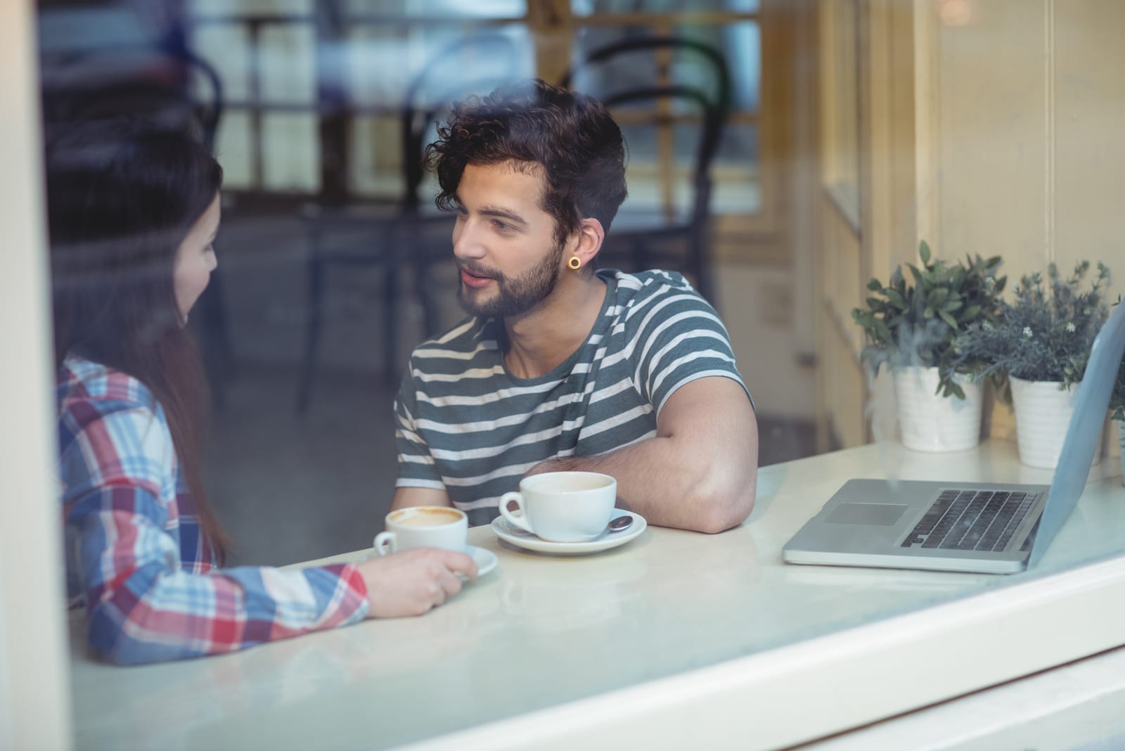 casal a conversar sentado à janela num café