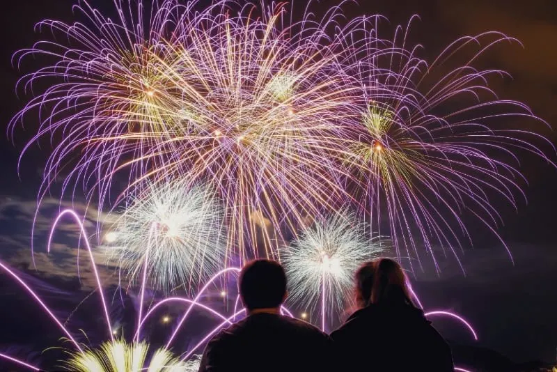 man and woman watching fireworks at night