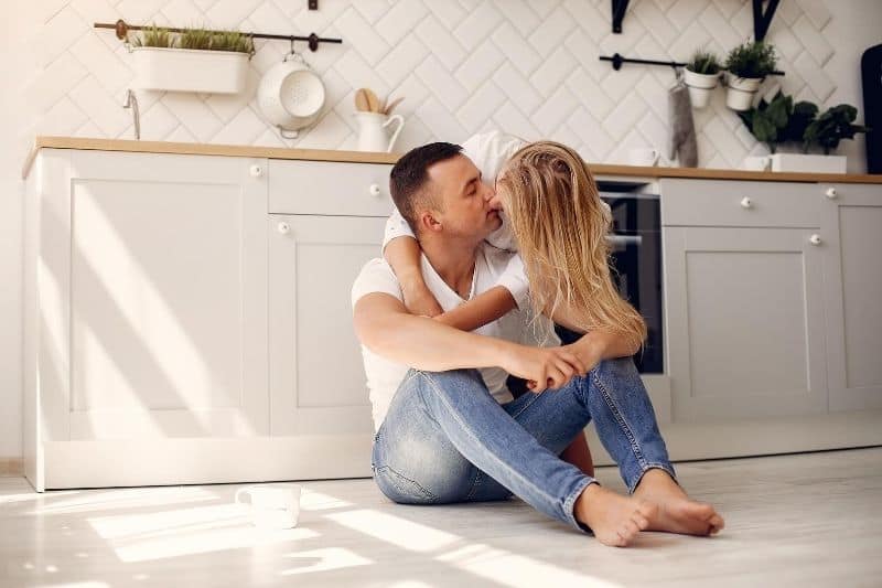 linda pareja besándose en la cocina hombre sentado en el suelo